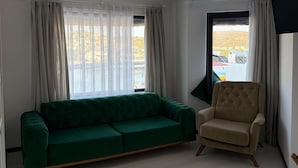 A living room with a green sofa, a beige armchair, and a large window with curtains. - Wb Weekend Otel  (Bodrum)