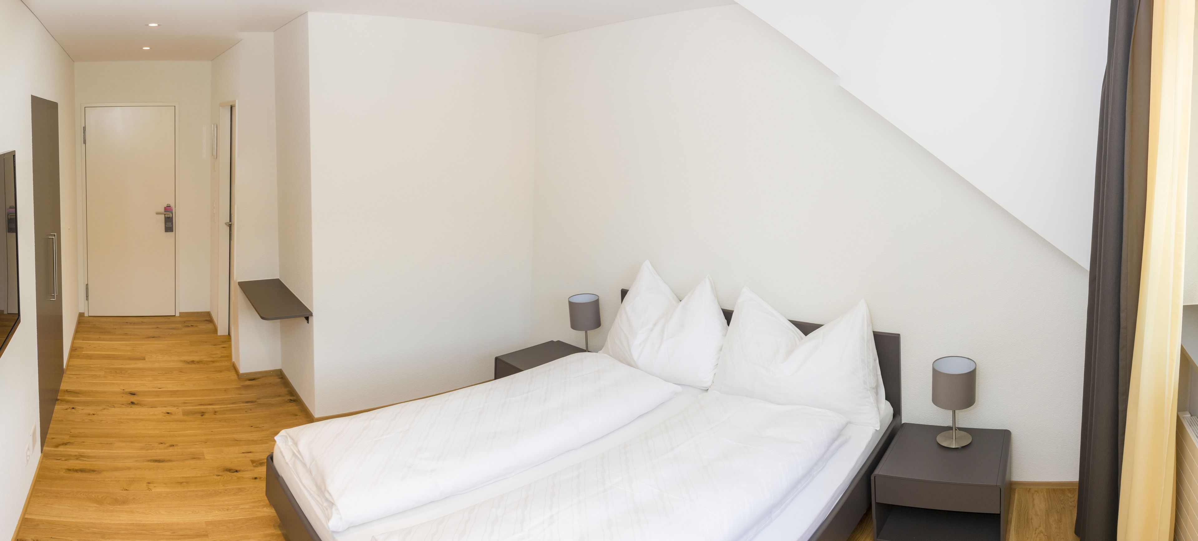 Ein Schlafzimmer mit einem Bett, Nachttischen, einer Lampe und einer Tür.