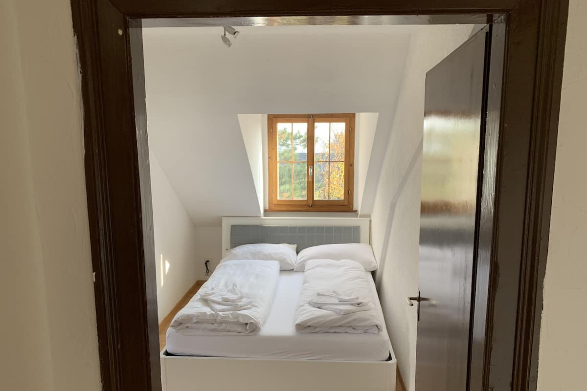 Quarto com cama, janela e porta.