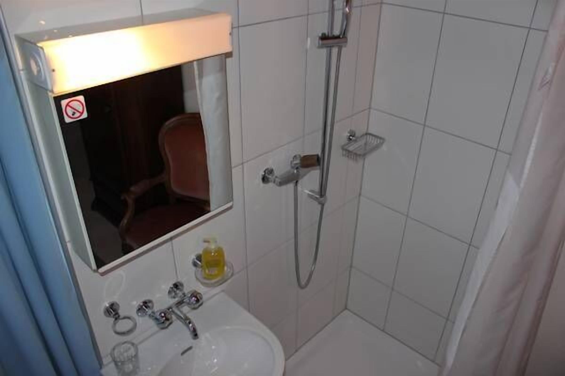 A bathroom with a white sink, mirror, and shower.