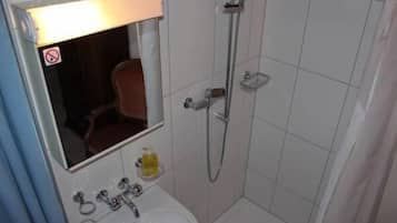 A bathroom with a white sink, mirror, and shower.