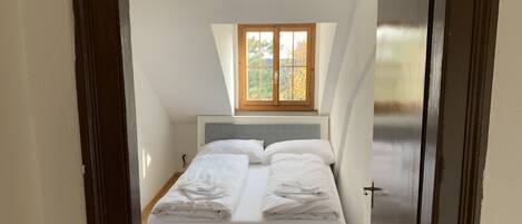 A bedroom with a bed, a window, and a door.
