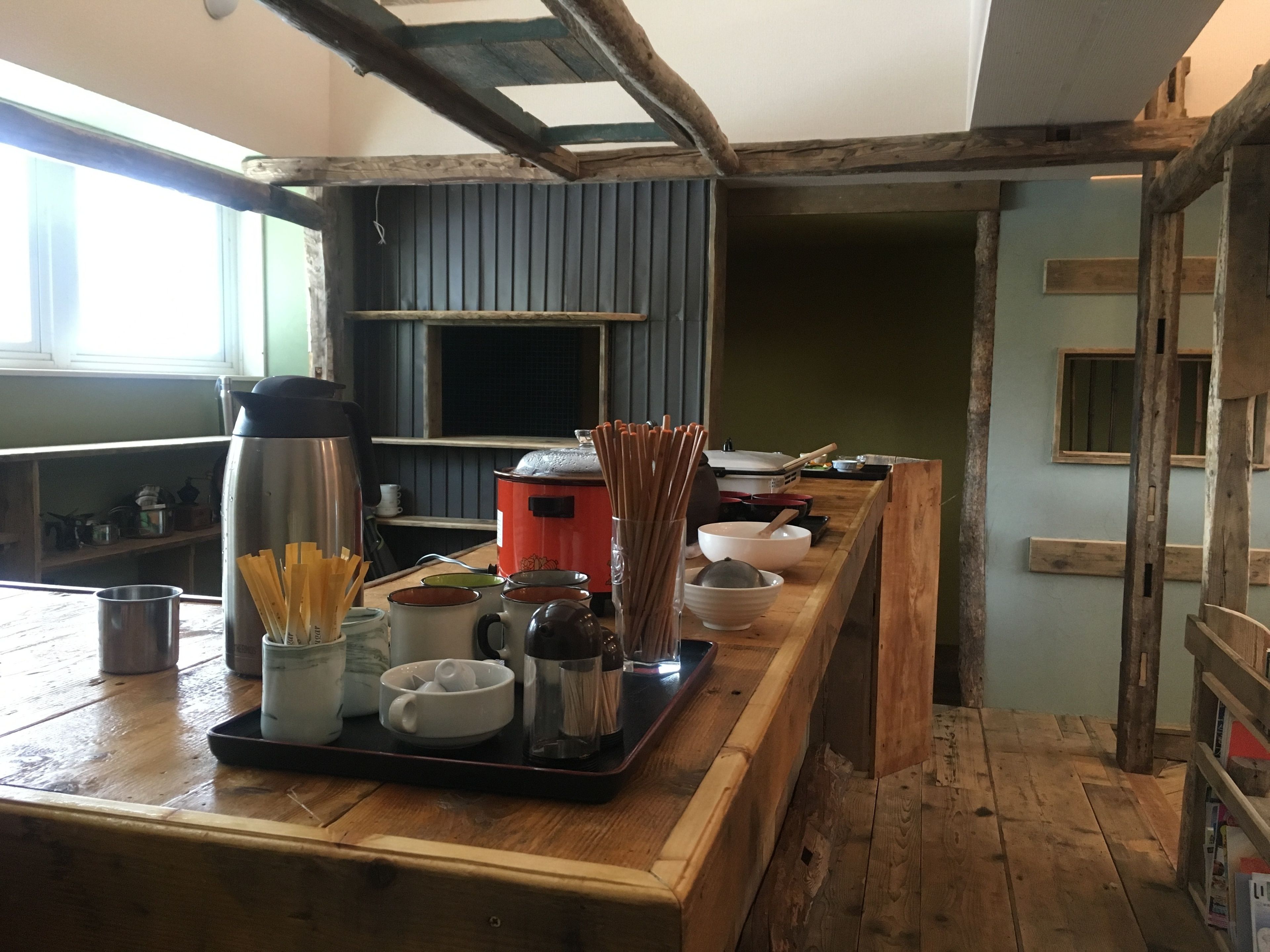 A kitchen with wooden beams, a stove, and various cooking utensils.