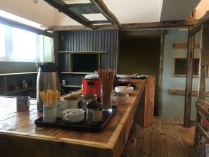 A kitchen with wooden beams, a stove, and various cooking utensils. - Biei Guest House Sirogane no Yu - Hostel (Biei)