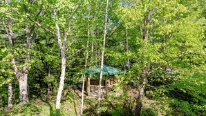 A wooden gazebo with a green roof surrounded by dense green foliage. - Biei Guest House Sirogane no Yu - Hostel (Biei)