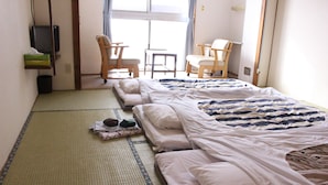 A hotel room with two beds, a television, and two chairs. - Biei Guest House Sirogane no Yu - Hostel (Biei)