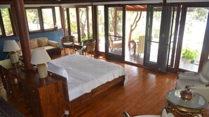Quarto espaçoso com uma cama grande, mobiliário de madeira e vista para uma área externa através de grandes portas de correr.