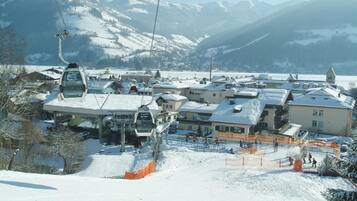 Een wintersportgebied met een stoeltjeslift, gebouwen en besneeuwde hellingen.