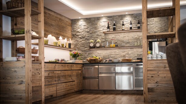 Una cucina moderna con mobili in legno, una parete decorata in pietra e elettrodomestici in acciaio inox.