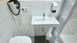 Un baño pequeño con inodoro blanco, lavamanos y ducha.