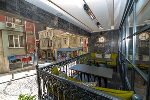 A hotel interior with a balcony overlooking a street, featuring a marble wall, a sign for 'HomeLike Hotel', and outdoor seating. - Homelike Hotel (Istanbul)