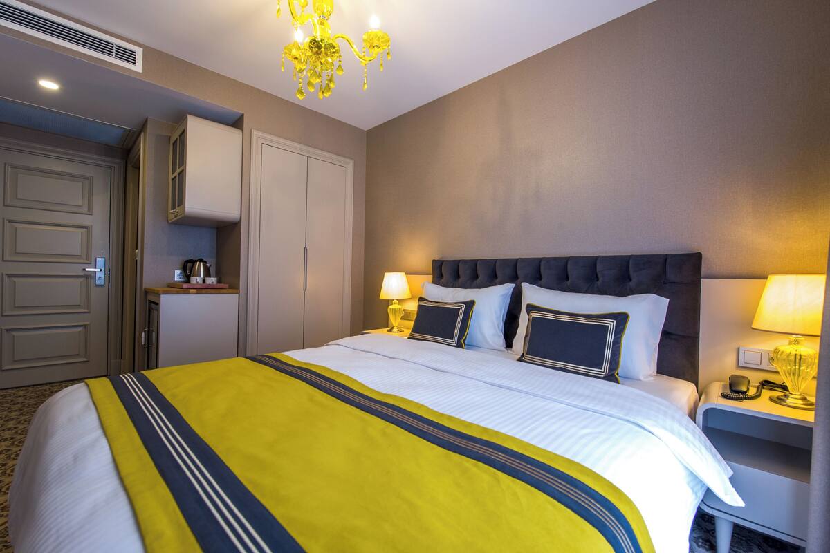 Ein Hotelzimmer mit einem großen Bett, Nachttischlampen, einer Kommode und einem Kronleuchter.