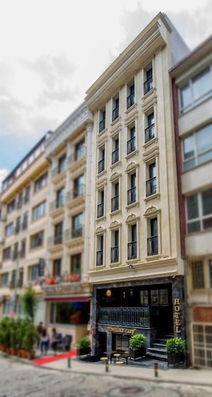 A hotel with a classic facade, multiple floors, and a red carpet entrance.