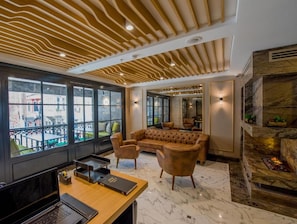 A modern lounge area with a sofa, chairs, a desk, and a fireplace.
