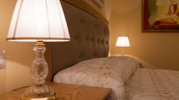 Un lit bien fait, recouvert d’une couvre-lit à motifs, avec une tête de lit capitonnée et une lampe de chevet posée sur une table de nuit en bois.