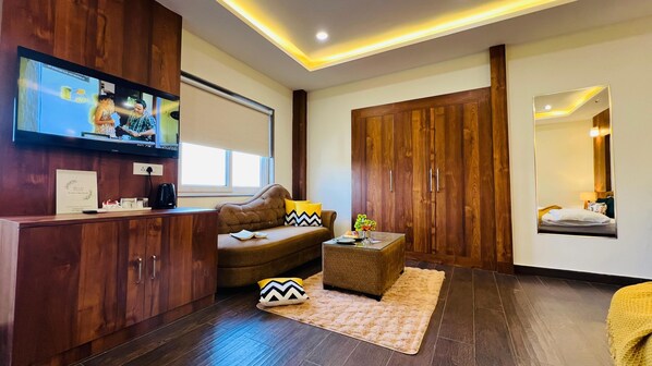 Una sala de estar moderna con sofá, mesa de centro y armario de madera. Un televisor está montado en la pared, y un espejo refleja parte del cuarto.