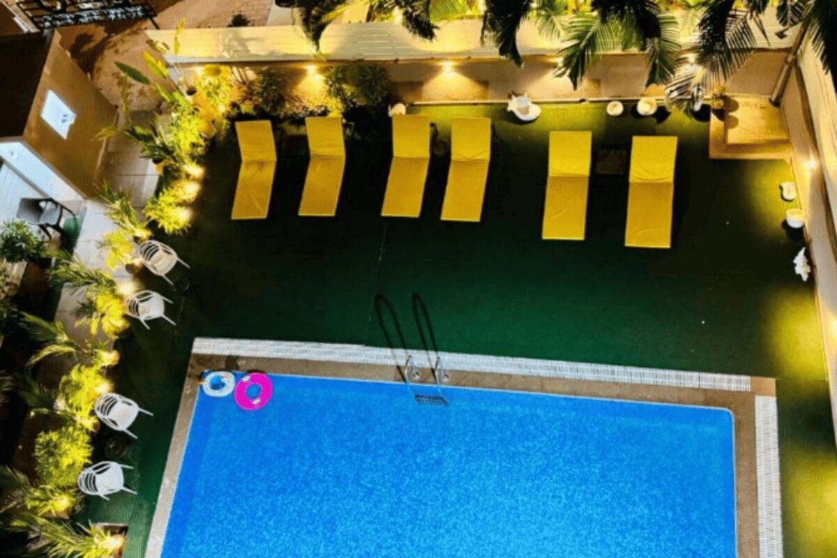 Ein Pool auf dem Dach mit glatter, blauer Wasseroberfläche, umgeben von gelben Liegestühlen und Topfpflanzen.