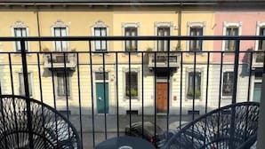 A balcony with two black chairs and a small table, overlooking a row of buildings with solar panels on the roofs. - Gatto Bianco Mia Aparthotel (Milan)