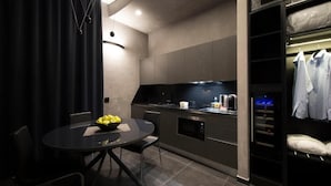 A modern kitchen with a dining area, including a round table with chairs and a bowl of fruit. - Gatto Bianco Mia Aparthotel (Milan)