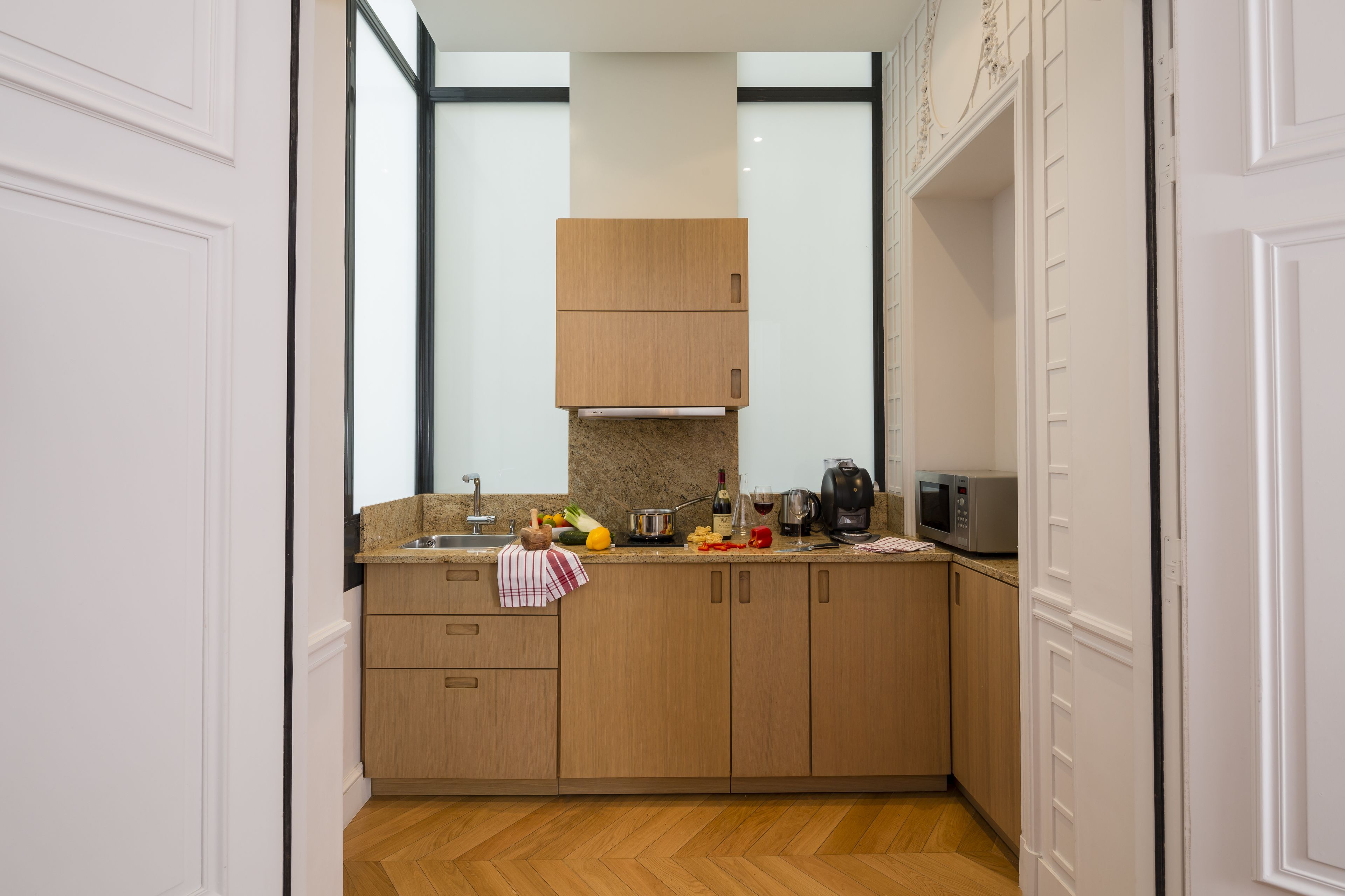 A modern kitchen with wooden cabinets, a granite countertop, and a stainless steel sink.