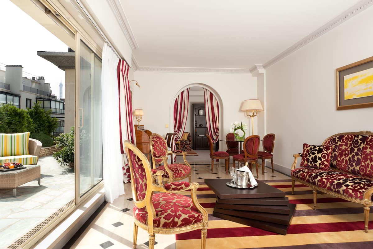 Een ruime woonkamer met een groot raam, een zithoek en een eethoek.