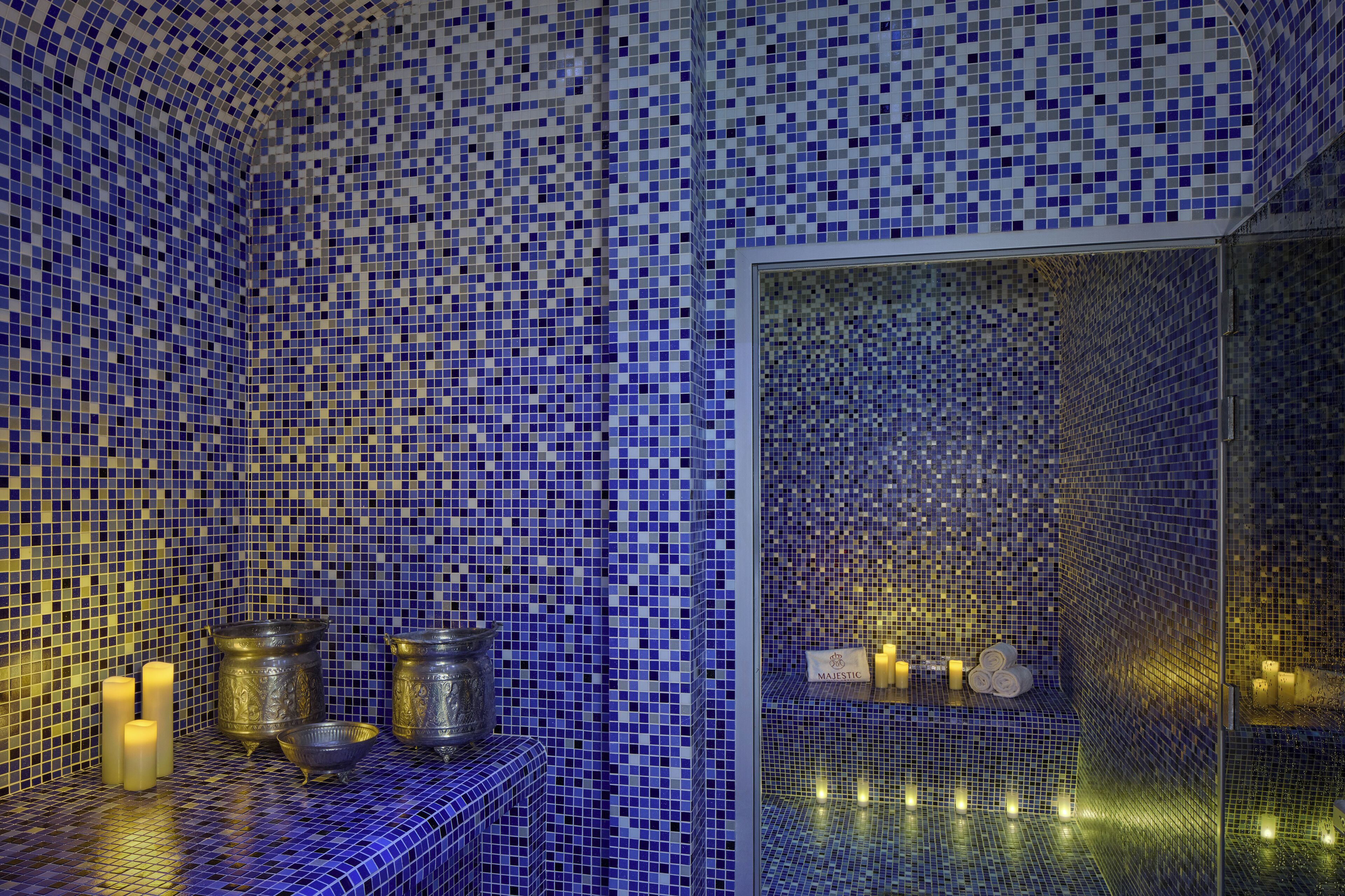 A bathroom with mosaic tile walls, a glass partition, and candles.