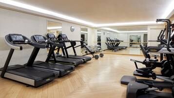 Une salle de sport équipée de tapis de course, de vélos elliptiques et d'appareils de musculation.