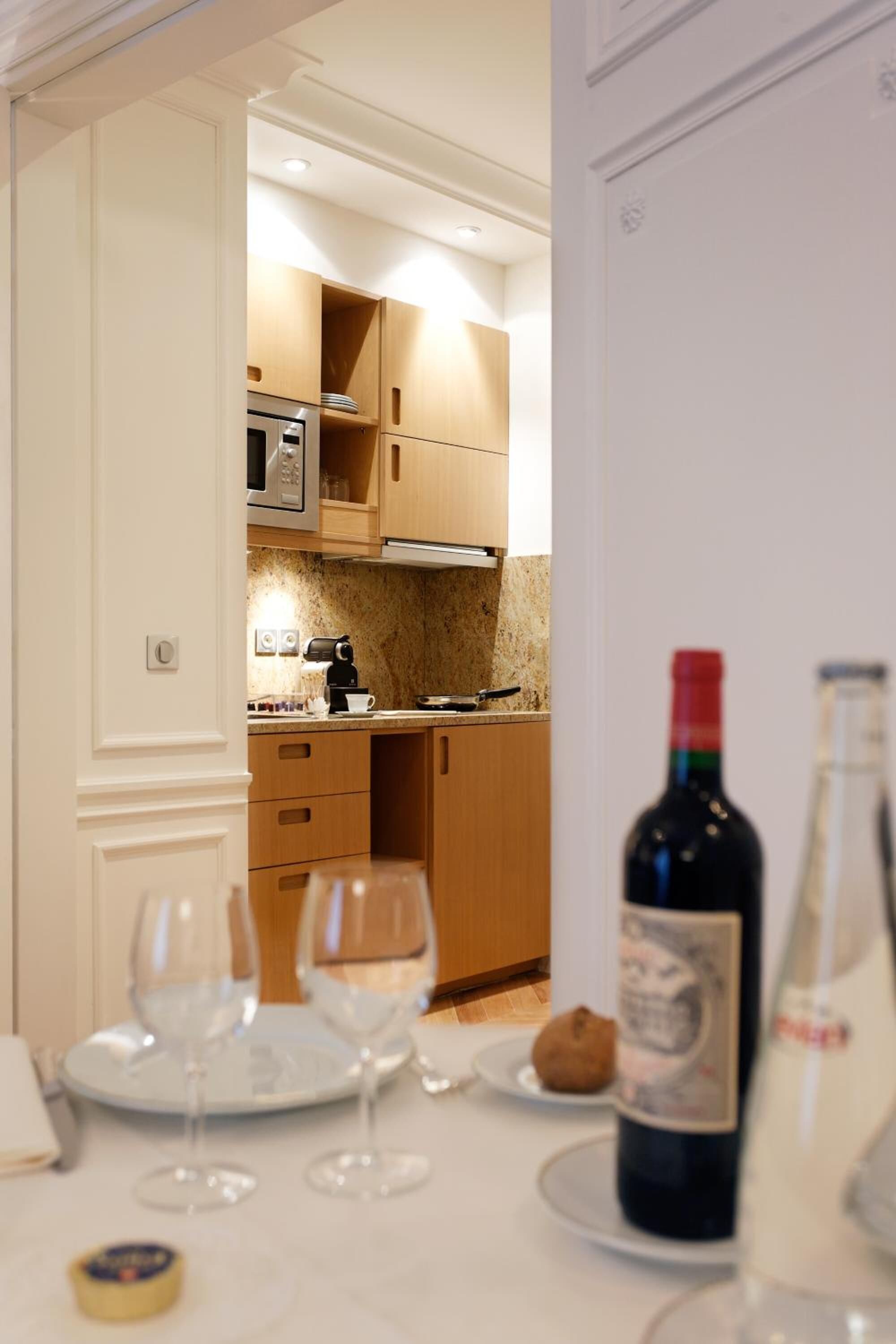 A dining area with a table set for two, a wine bottle, and a bottle of water.