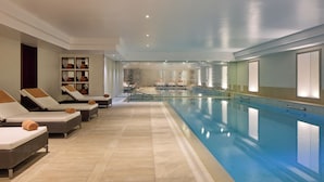 A swimming pool area with lounge chairs and a tiled floor.