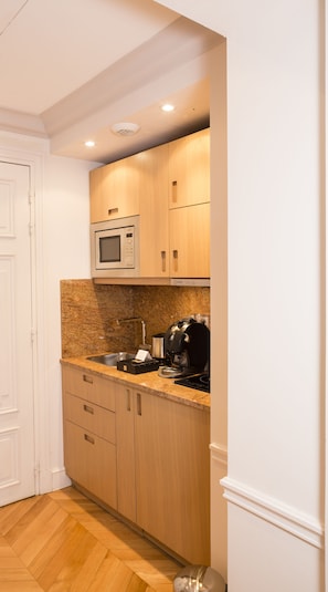 Compact kitchen with modern design, featuring a microwave oven, coffee maker, and toaster.