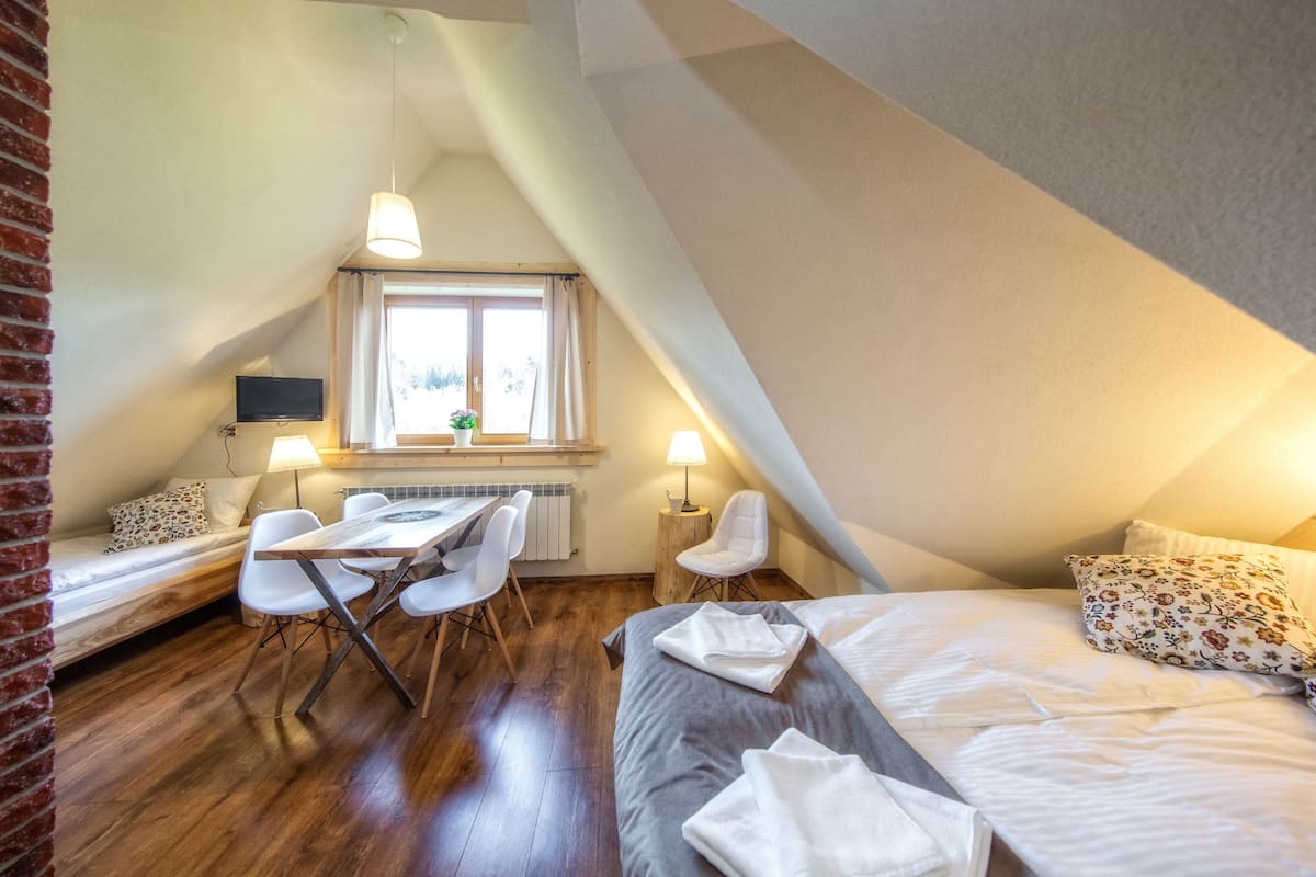 Ein gemütliches Schlafzimmer im Dachgeschoss mit einem Bett, einem Schreibtisch und einem Fenster.