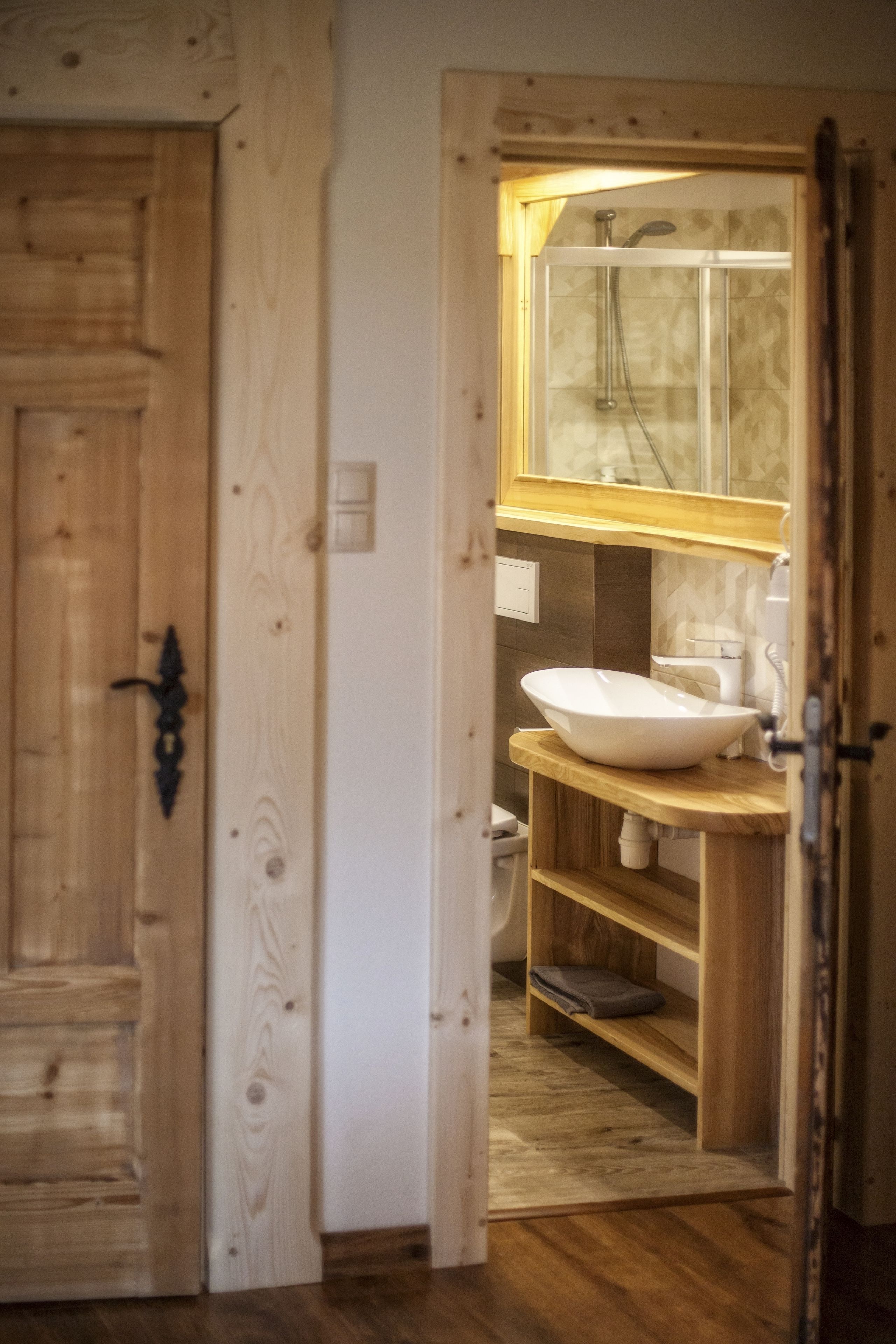 A wooden door with a glass panel, a wooden vanity with a sink, and a shower area with a glass door.