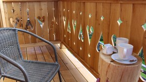 A wooden deck with a wicker chair and a small table with cups and a spoon. - Willa Giewontka (Koscielisko)