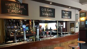Eine Barbereich mit Schild, das Happy Hour von 17 bis 19 Uhr täglich, einen WLAN-Code und Schwimmbadnutzung an jedem zweiten Abend anzeigt.
