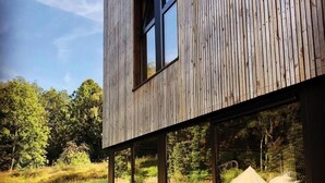 Un bâtiment moderne doté de grandes fenêtres et offrant une vue sur un espace verdoyant où sont installées des tentes.