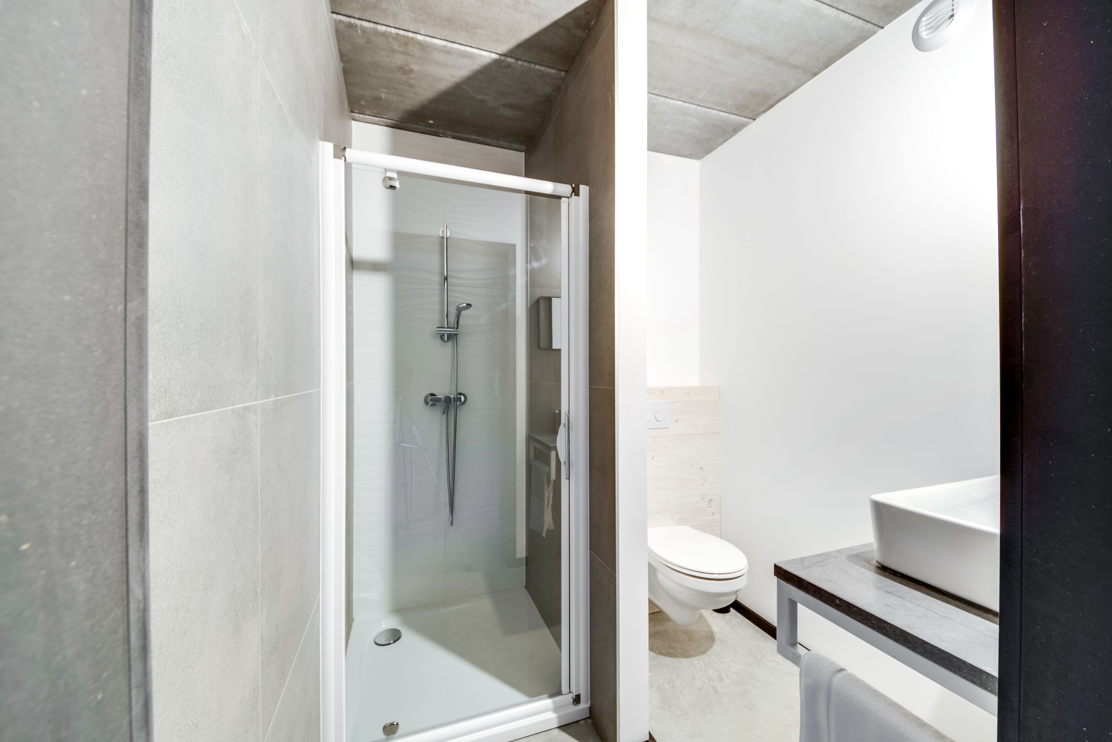 A modern bathroom with a glass-enclosed shower, a white toilet, and a marble countertop.