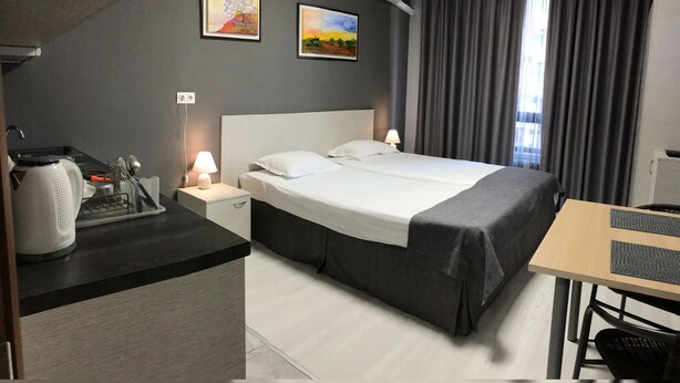 A hotel room with a bed, bedside table, lamp, and artwork on the wall. - ATM Aparts Sofia (Sofia)