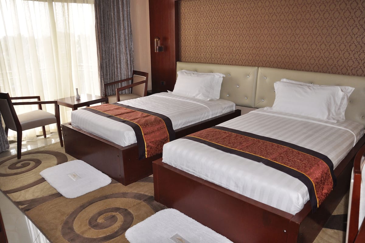 A hotel room with two beds, a desk, and a chair.
