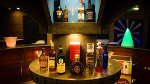 Eine Bar mit verschiedenen Spirituosenflaschen und einer neonfarbenen Weihnachtsbaumdeko.