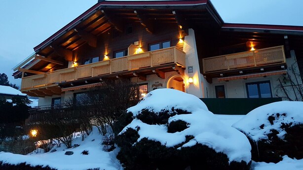 Een gebouw met twee verdiepingen, een balkon, houten leuningen en een met sneeuw bedekt dak.