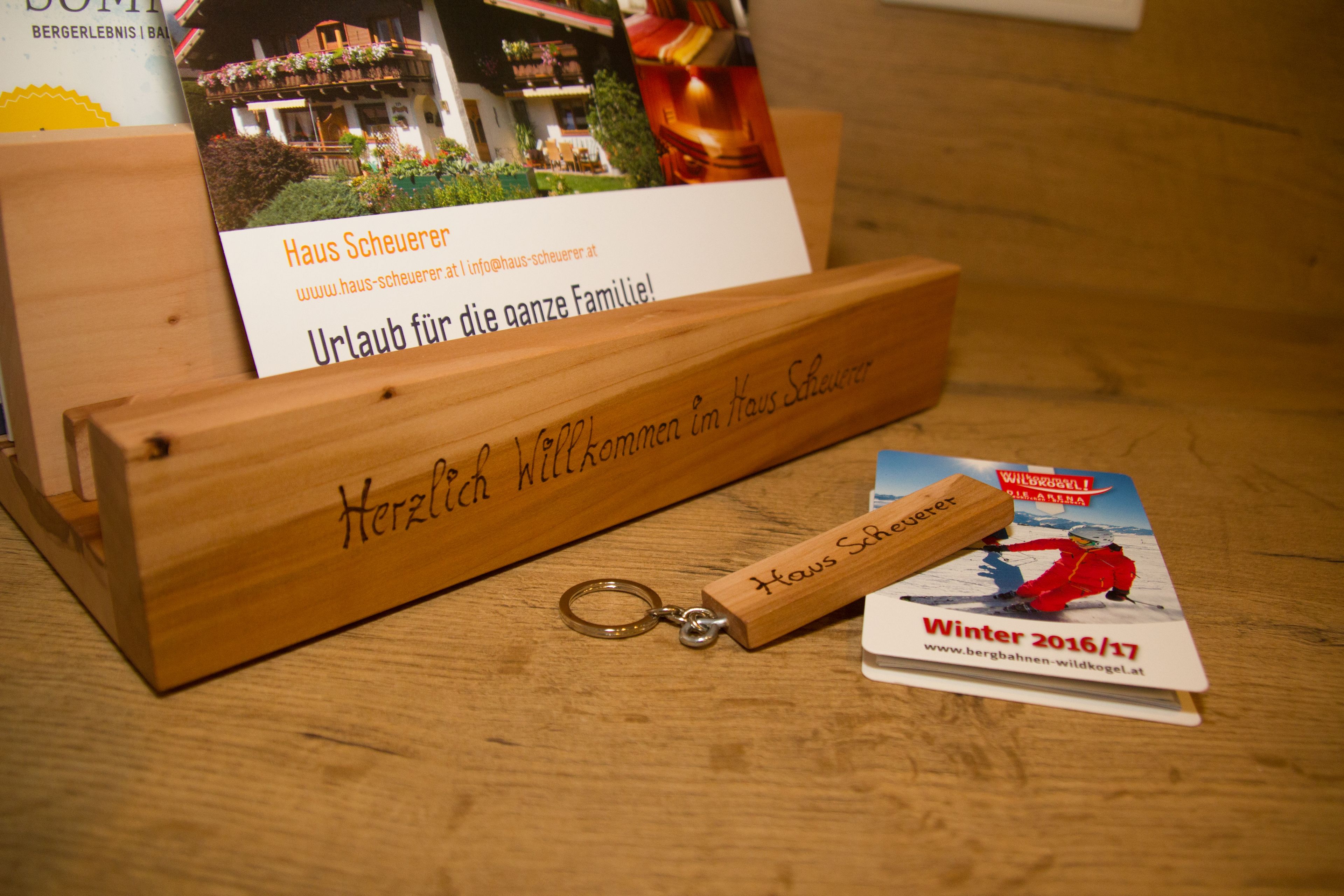 A wooden key holder with a key and a postcard.