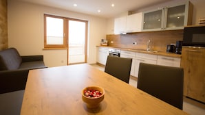 Een moderne keuken met houten kastjes, een eettafel en een schaal met fruit.