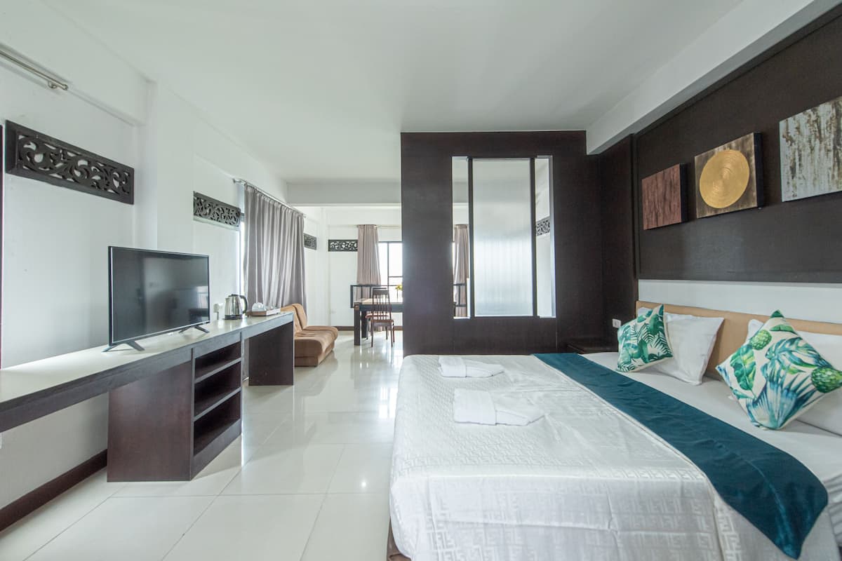 Habitación de hotel moderna con una cama grande, televisión, escritorio y vistas al comedor.