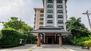 A multi-story hotel with a covered entrance, surrounded by greenery. - The Wing Design Hotel (Bangkok)