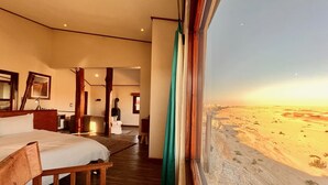 Una habitación con una cama, muebles de madera, un escritorio y vistas a un paisaje desértico.