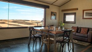 Un comedor con vistas a las dunas de arena, una mesa de madera y un sofá de cuero.