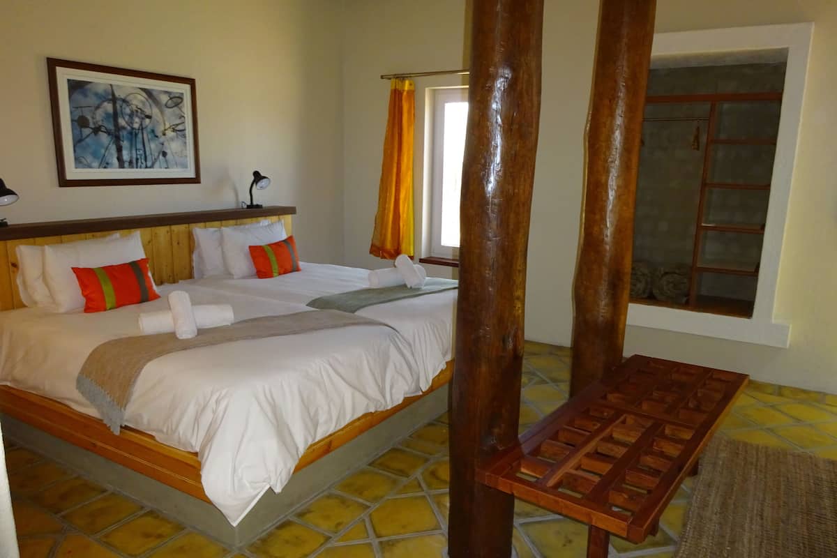 Une chambre d’hôtel avec un grand lit, une tête de lit en bois et une fenêtre avec des rideaux.