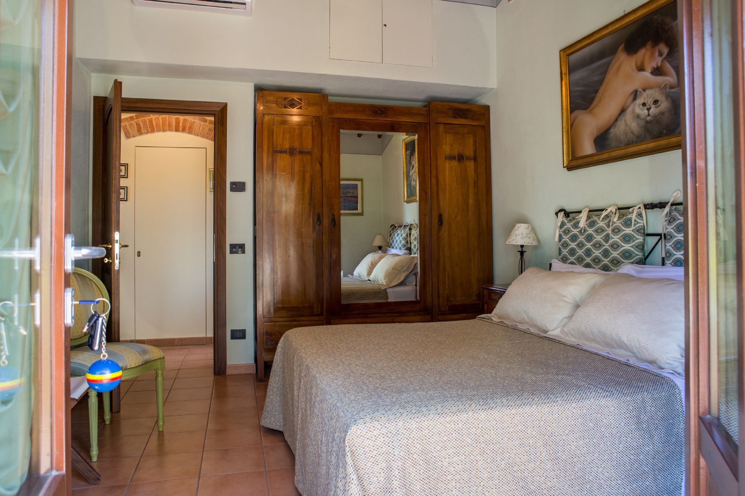 Ein Schlafzimmer mit Bett, Stuhl, Spiegel und Kleiderschrank.