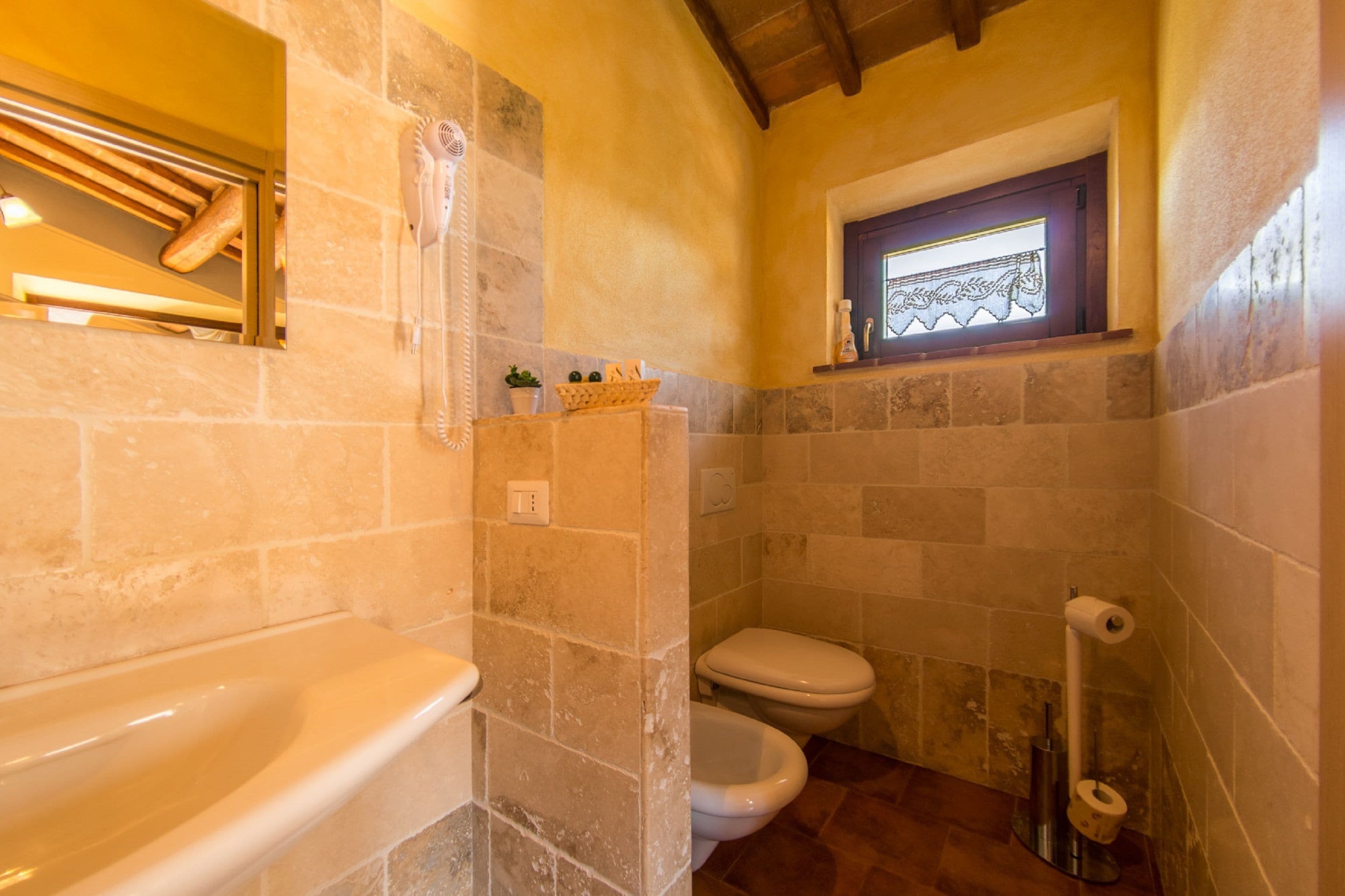 Une salle de bain avec une baignoire, des toilettes et une petite fenêtre.