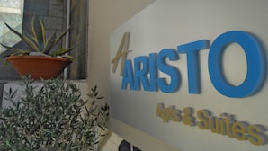 A sign for 'ARISTO Apts & Suites' with a potted plant and some foliage in front. - Aristo (Hersonissos)
